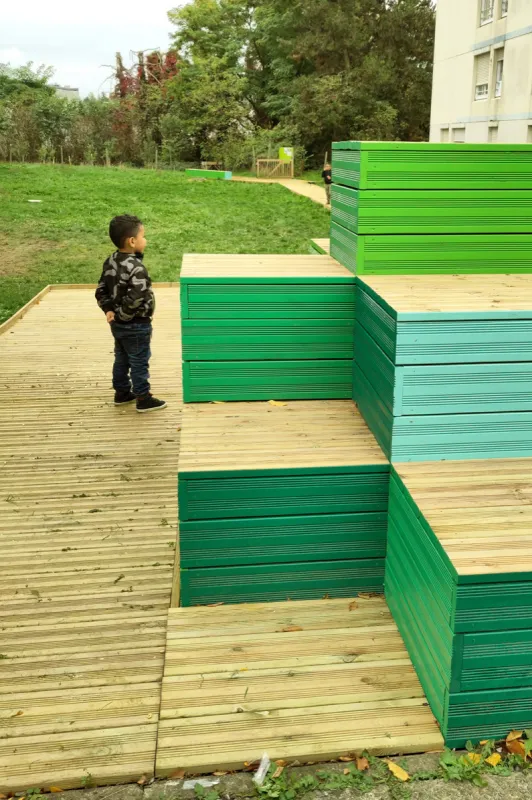 Gradins en bois peint en vert, un enfant au sommet